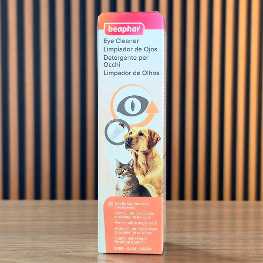 Beaphar Eye Cleaner box for pets, featuring a dog and cat illustration, standing on a wooden surface against a wooden slatted background.