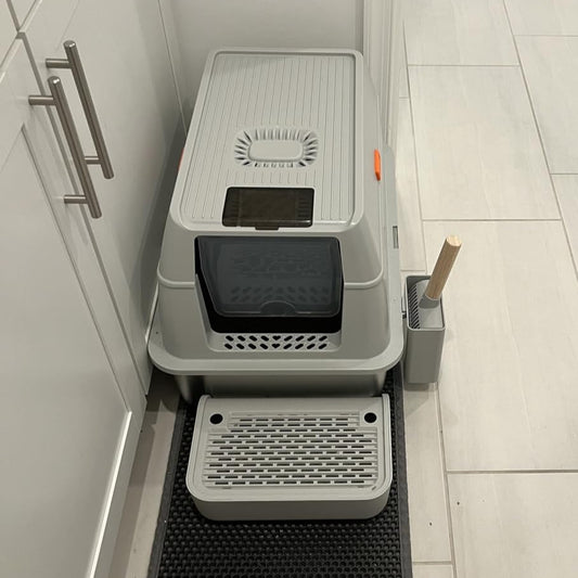 Pet litter box system with automatic cleaning mechanism on a tiled floor.